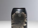 un vase noir orné d'une fleur, posé sur une table