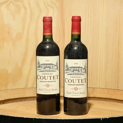 two bottles of wine sitting on top of a barrel