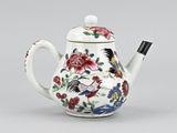 a white teapot with a floral design and a bird on it
