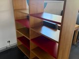 a room with a desk, shelves, and a chair in it