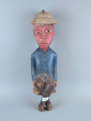 une vieille statue en bois d'un homme avec un chapeau sur la tête