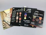 trois livres posés sur une table, sur lesquels sont posées des médailles