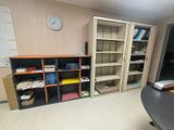 a room with a desk, bookshelf and a clock on the wall