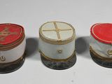 three small tins are lined up in a row on a white surface
