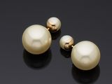 deux paires de boucles d'oreilles en perles et en or sur un fond noir
