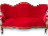 un canapé rouge posé sur un parquet, près d'un mur blanc