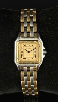 une image représentant une montre-bracelet dorée et argentée posée sur une surface noire