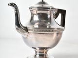 an antique silver teapot with a handle on a white surface