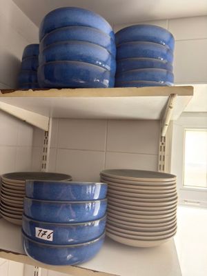 many plates and bowls on the shelves in the kitchen