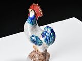 a figurine of a rooster on a white surface