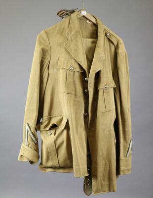 an old jacket hanging on a hanger on a gray wall