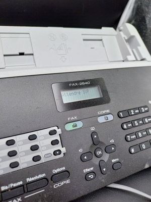 a black and white photo of a fax machine on a desk