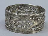a close up of a silver bracelet on a white surface