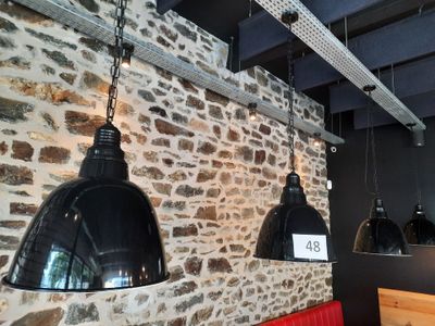 three black lamps hanging from the ceiling of a restaurant