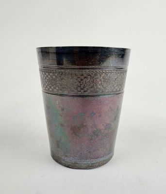 a metal cup with a pattern on it on a white surface