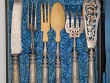 a silverware set in a blue box with a spoon, knife, and spoon rest