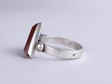 a close up of a silver ring with a red stone in it