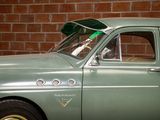 a green car parked in front of a brick wall