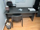 a desk with a chair and a lamp in the corner