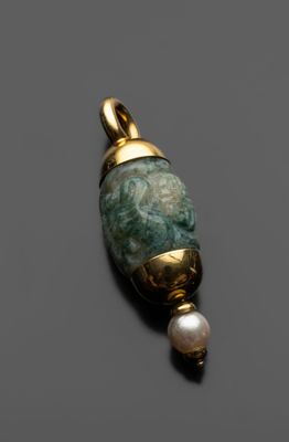 un gros plan d'un pendentif composé d'une pierre verte et d'une perle, posé sur une surface noire