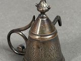 a small silver teapot with a handle on a table