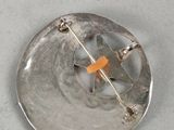a silver button with an orange cross on it