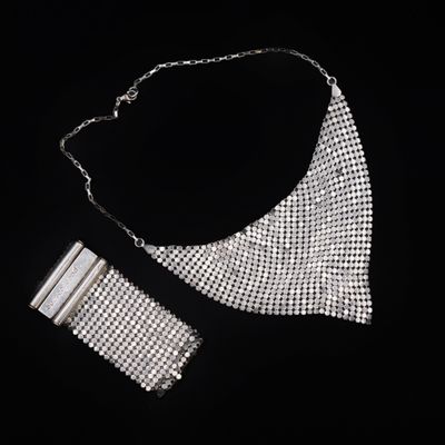 une image représentant un collier et un bracelet en argent sur fond noir