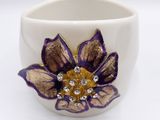 a white cup with a purple and gold flower on it