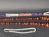 trois rangées de perles et un collier sur un fond noir