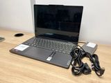 un ordinateur portable posé sur un bureau en bois, avec son chargeur