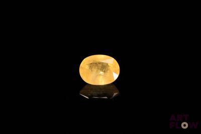 a yellow sapphire stone on a black surface