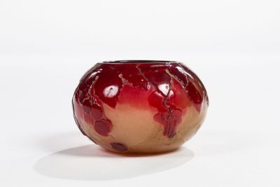 a red and gold vase sitting on a white surface