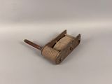 un vieux porte-brosse de toilettes en bois, muni d'un manche en bois, posé sur une surface blanche