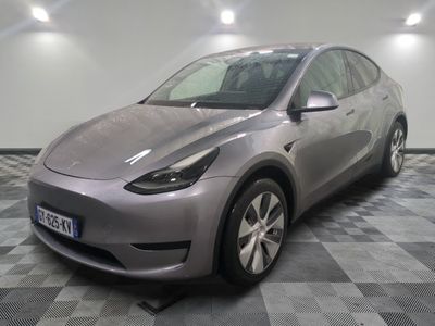 the silver tesla model y is parked in a room with a checkered floor