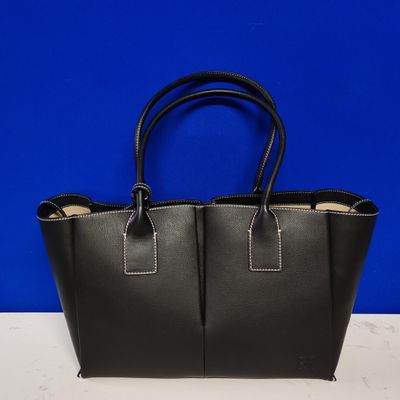 a black leather tote bag on a white table with a blue background