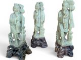 trois statues représentant des personnes d'origine asiatique sont posées sur une souche d'arbre