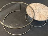 two round coffee tables with glass tops on a black surface