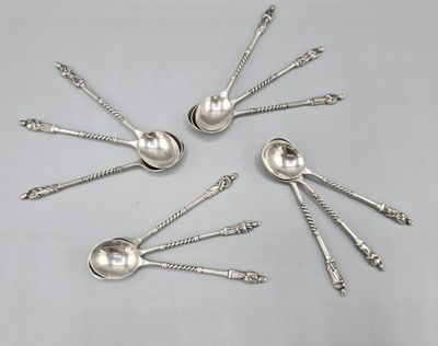 six cuillères en argent sont disposées en cercle sur une table