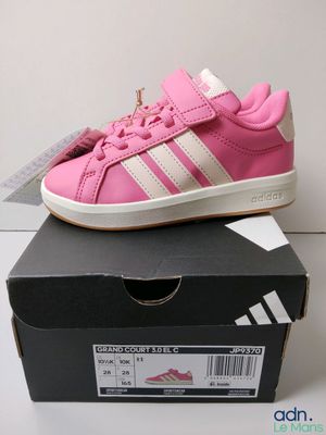 Des baskets Adidas roses et blanches sont posées sur une boîte