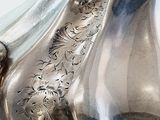 a silver vase that has a horse on the side of it