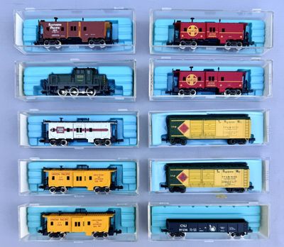 six different train cars in plastic containers on a blue surface