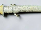 a silver and gold object on a white surface