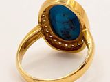 a close up of a gold ring with a blue stone in it