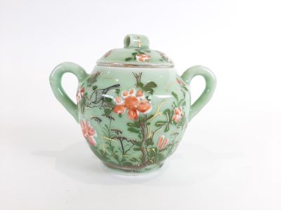 une théière verte décorée d'un oiseau et de fleurs