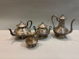 three silver teapots and a coffee pot on a table