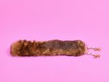 un cache-oreilles en fourrure marron posé sur une surface rose
