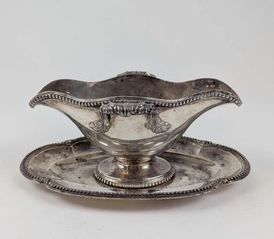 une assiette en argent posée sur une soucoupe, avec une autre soucoupe à côté