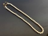 a white pearl necklace on a black surface