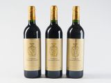 three bottles of red wine sit side by side on a white surface