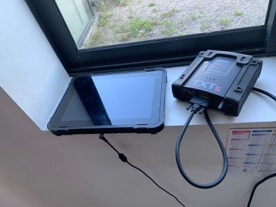 une tablette posée sur le rebord d'une fenêtre, à côté d'un téléphone
